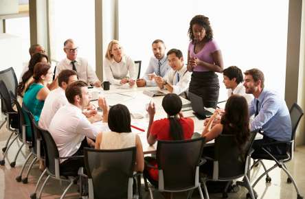 Businesswoman Addressing Meeting Around Boardroom Table